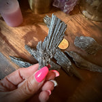 Hand holding a crystal on a wooden surface with candles and crystals in the background