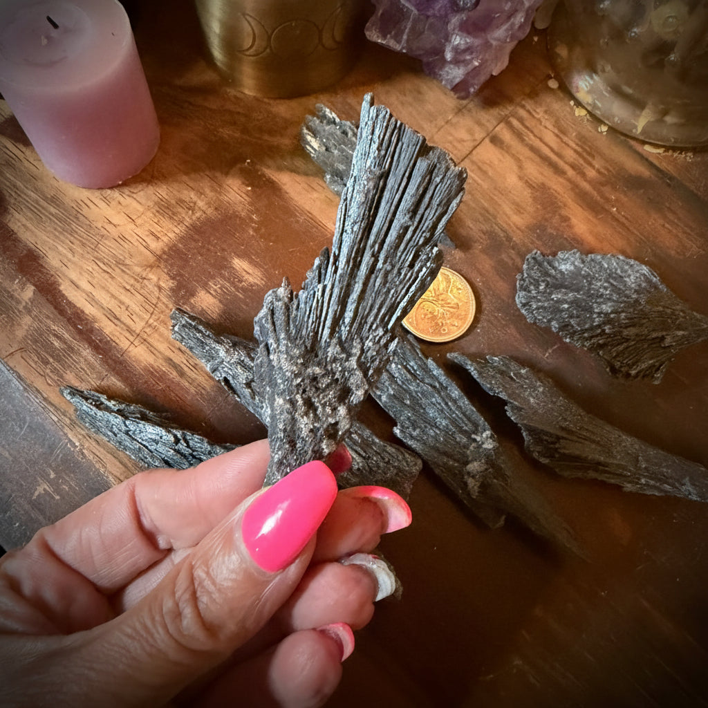 Hand holding a crystal on a wooden surface with candles and crystals in the background