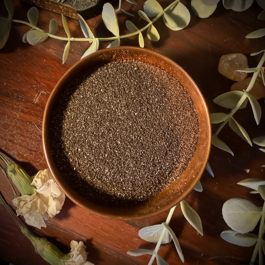 Wooden bowl filled with gold magnetic sand on a decorative surface with leaves and flowers.
