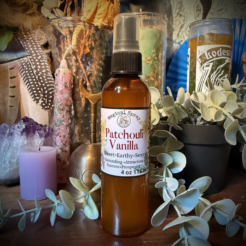 A bottle of Patchouli Vanilla body spray by The Art of Scent, displayed on a wooden surface with decorative dried flowers, eucalyptus leaves, crystals, and a purple candle.