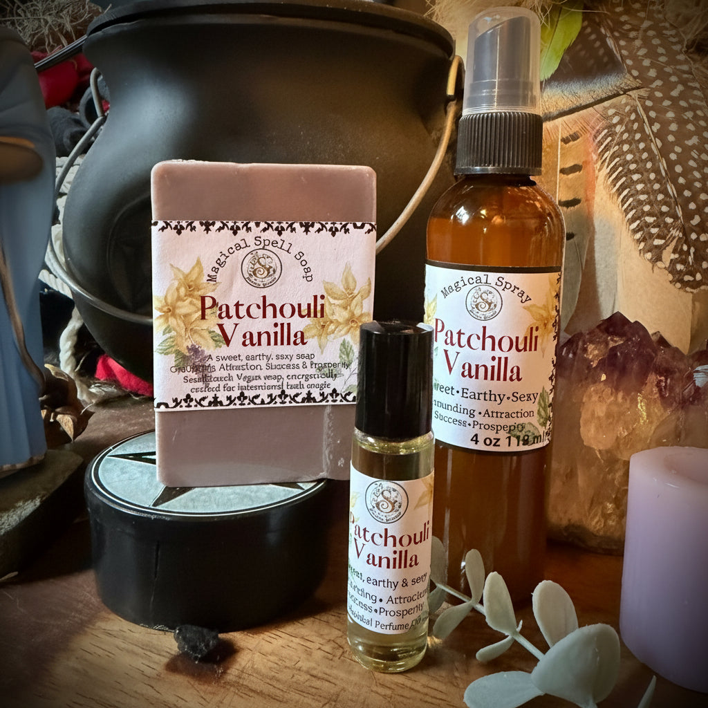 A bath and body gift set from Sweet Wildflower Soap featuring a Patchouli Vanilla soap bar, a matching spray bottle, and a roller bottle, arranged on a rustic wooden surface with a black cauldron and dried botanicals.