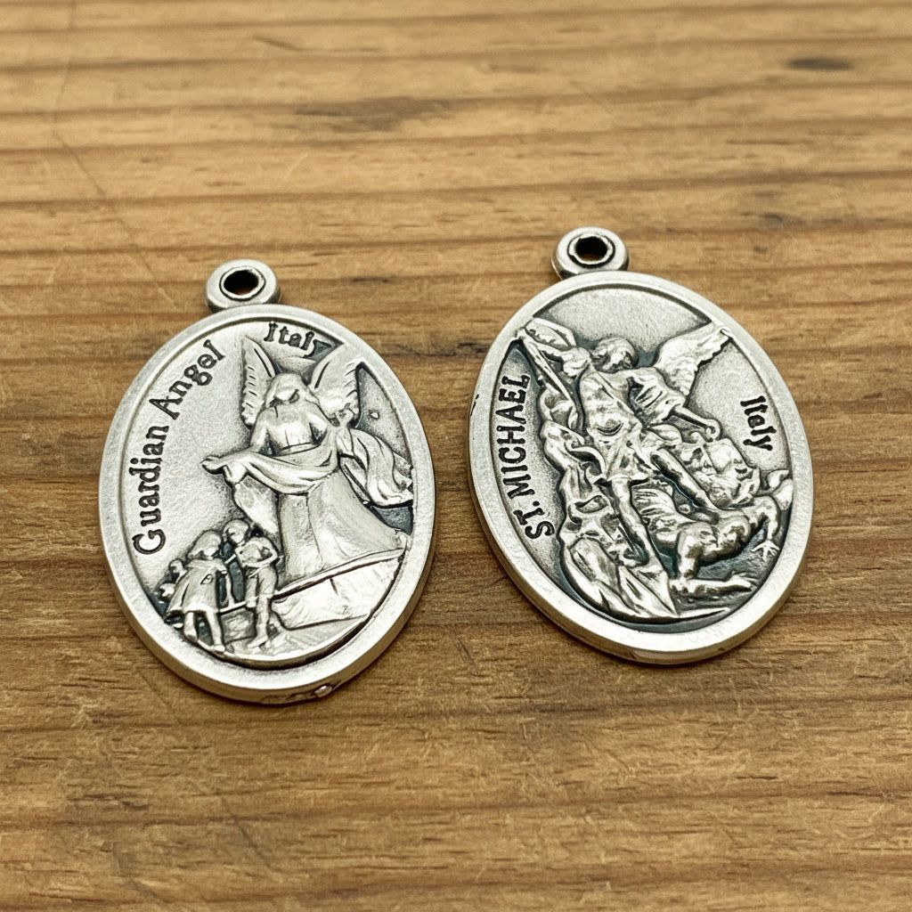 Two oval silver-tone religious medallions showing St. Michael and Guardian Angel designs, displayed side by side on a plain white background.