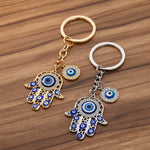 Two keychains with eye-shaped charms on a beige fabric background