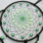 Dreamcatcher with green beads on a white background