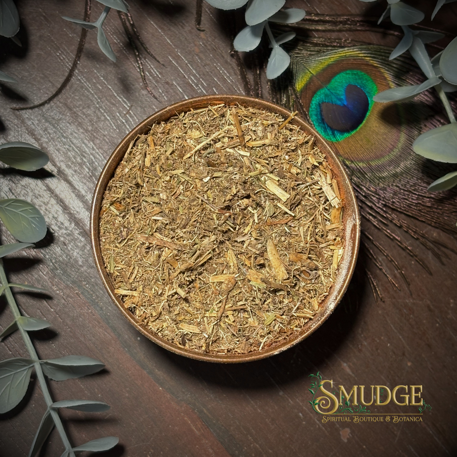 Dry herbs in a bowl on a wooden surface with eucalyptus leaves and a peacock feather, featuring the brand 'Smudge'.