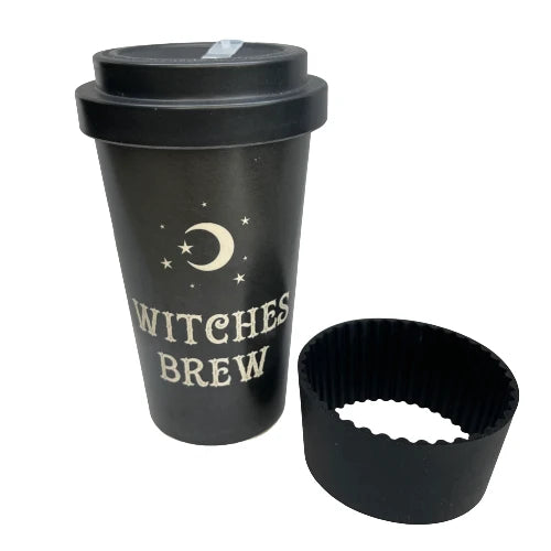 A black reusable travel tumbler with a matching black lid, printed with a gold crescent moon, stars, and the words 'WITCHES BREW,' shown next to a black silicone cupcake liner on a white background.