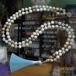 Decorative necklace with beads and a tassel in front of a store shelf.