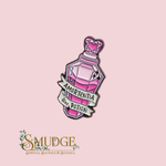 A pink and purple faceted potion bottle enamel pin with a banner reading 'AMORTENTIA love POTION', shown on a light pink background above the Smudge Spiritual Boutique & Botanica logo.