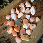 Apricot pink agate stones on a wooden background with a canadian quarter beside them.