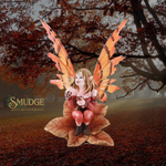 A fantasy fairy figurine or statue seated on a large leaf in an autumn forest setting, with orange and brown wings, pointed ears, and a pinkish dress. The brand name 'SMUDGE' appears in the lower left corner.