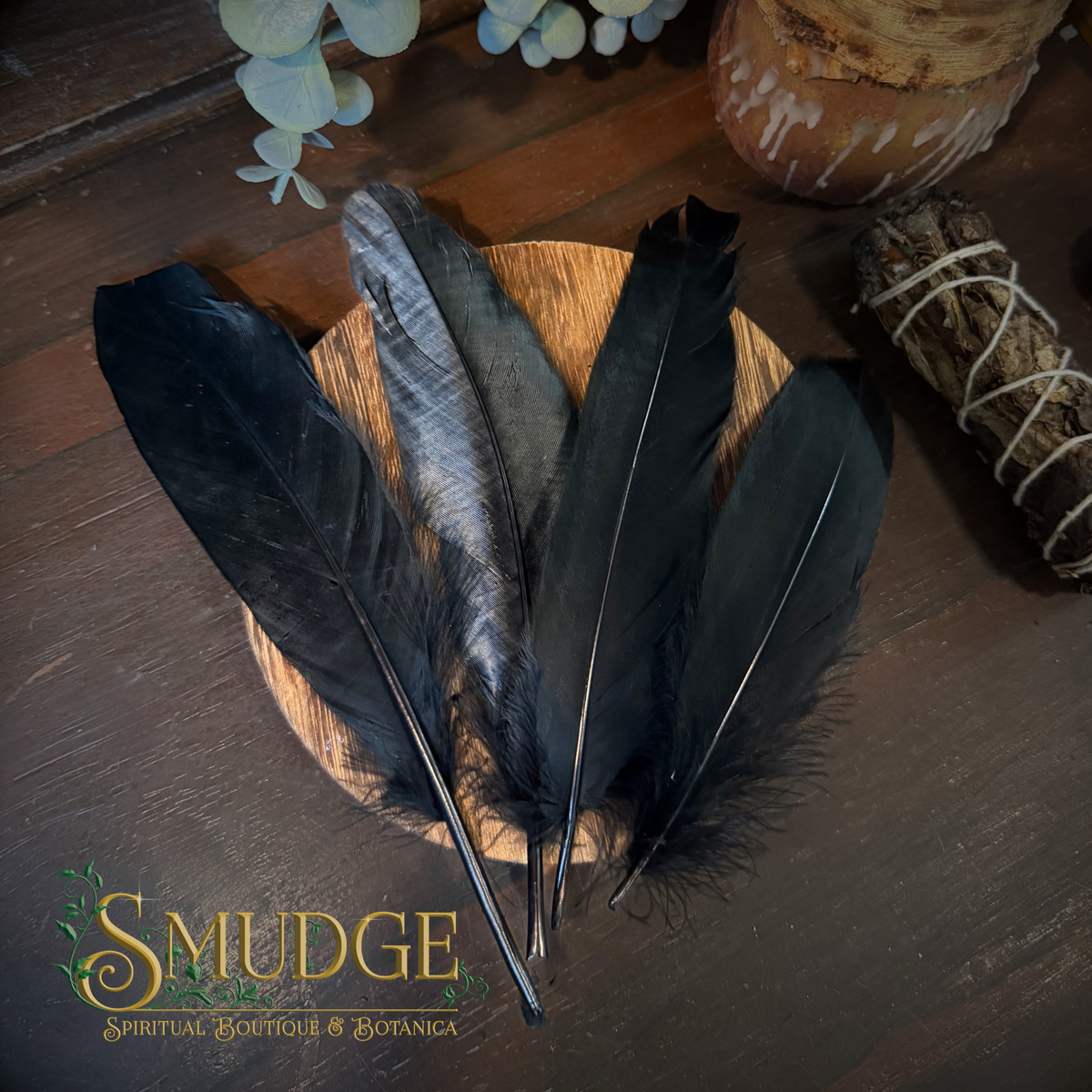 four black birds feathers on a wooden table