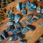 Blue apatite tumbled stones on a wood background with a Canadian quarter in the middle.