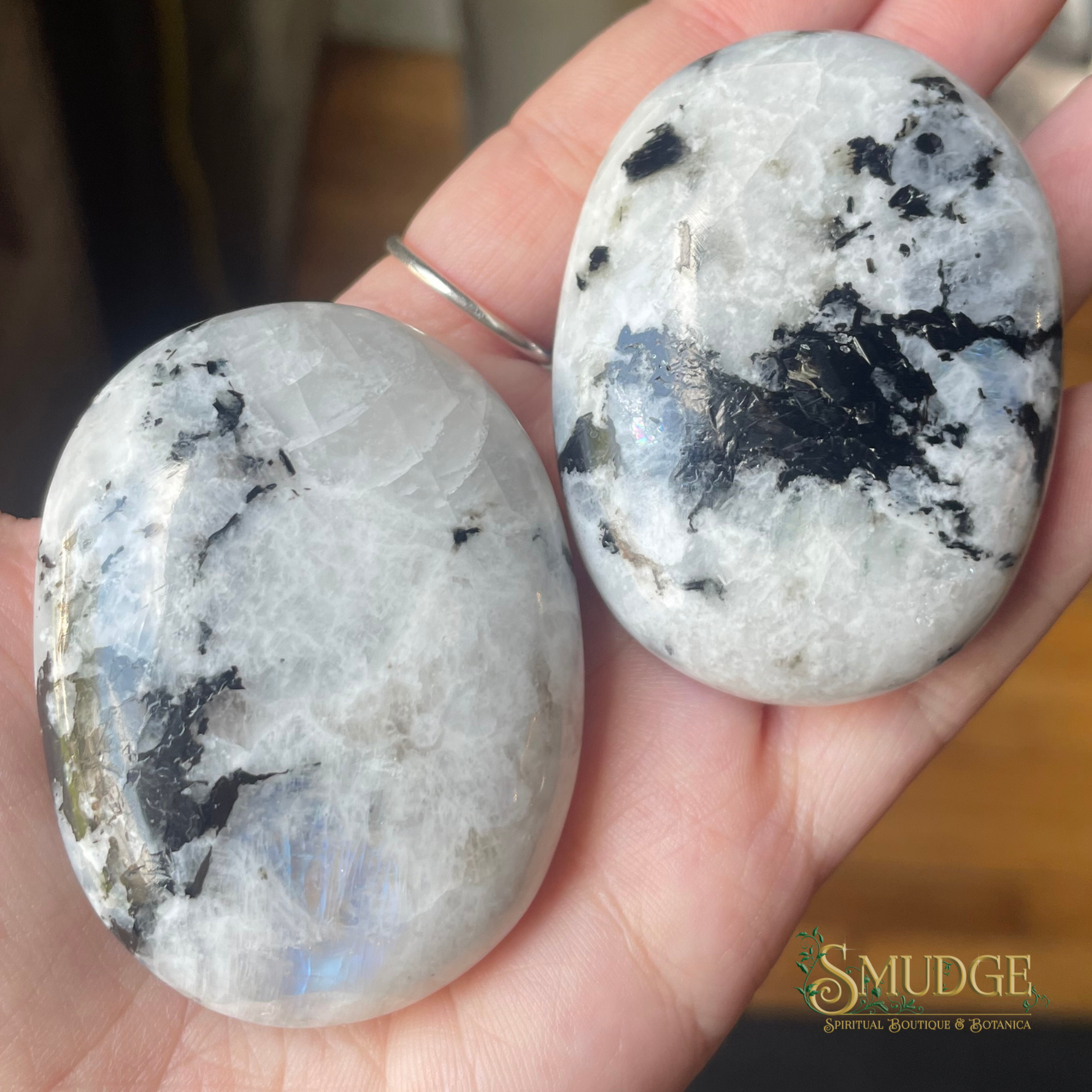 Two polished stones held in a hand with 'Smudge' brand logo in the corner.