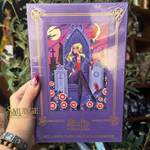 A hand holds a shrink-wrapped purple tarot deck box with an illustrated cover featuring a blonde woman in a graveyard scene. The box has gold decorative border lines and text reading 'Buffy the Vampire Slayer' and 'Mega Sized Tarot Deck and Guidebook.