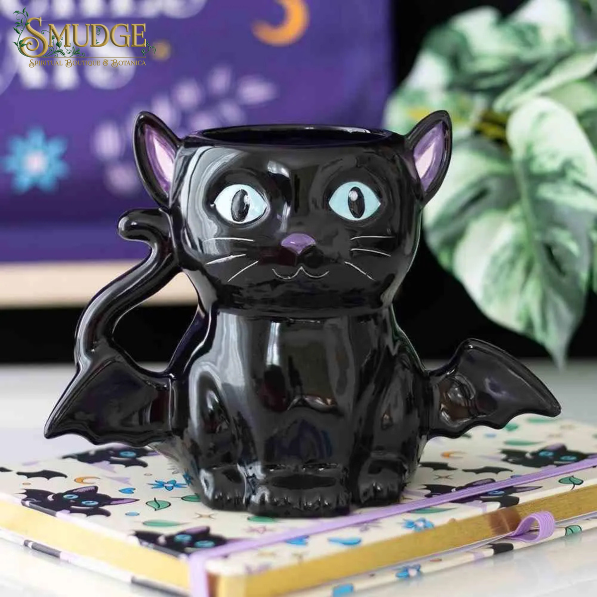 Cat Bat shaped ceramic mug on a notebook, purple background and Smudge logo top left corner