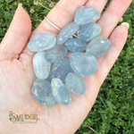 Blue transparent stones in a hand with grassy background and Smudge logo