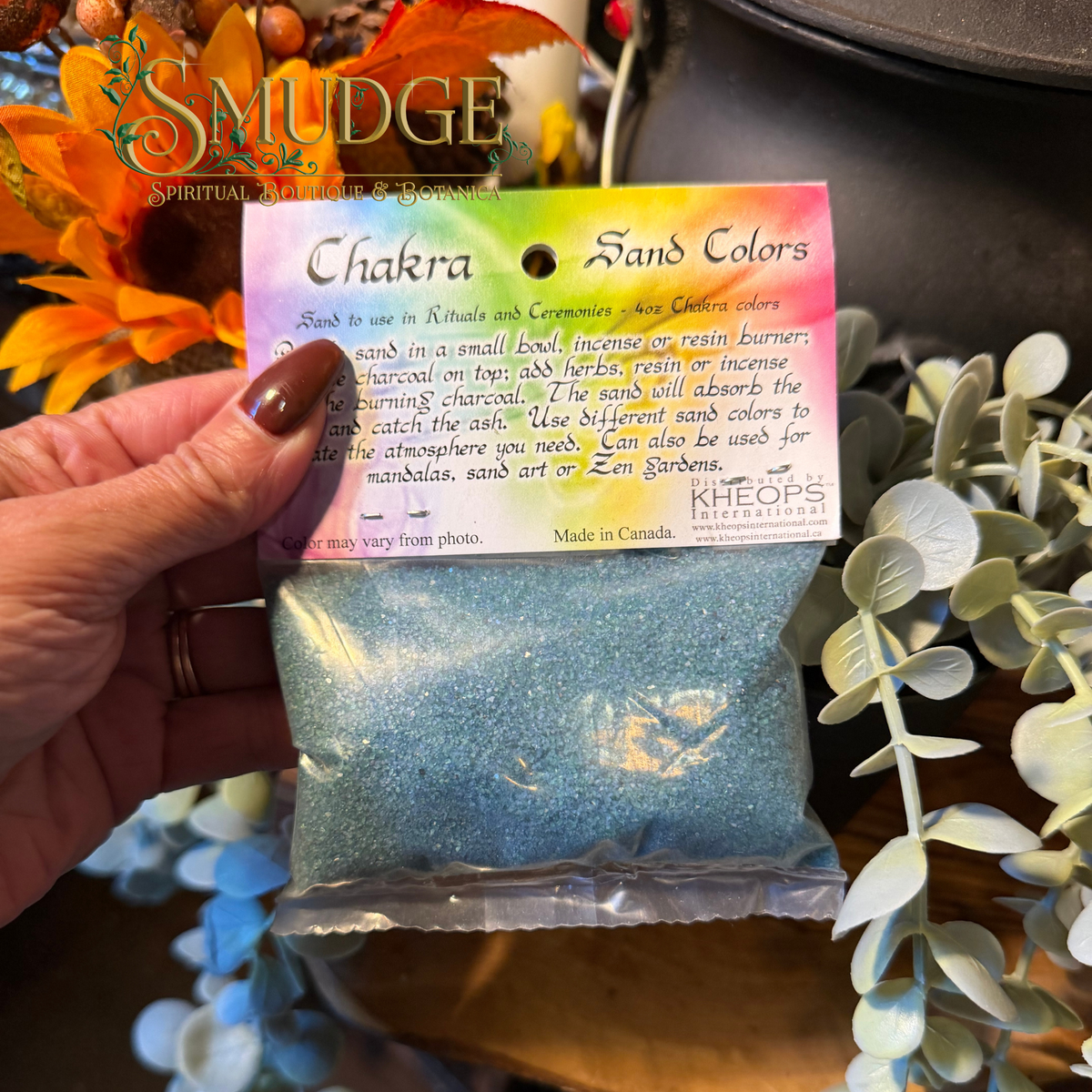 hand holding a bag of blue coloured sand labeled chakra colour sand.
