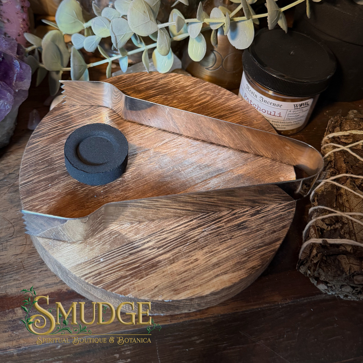 A wooden incense burner set with a metal tray and a small black incense holder, styled on a wooden surface with botanical props and a visible Smudge brand logo.