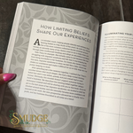 An open book or booklet showing printed pages with the title 'HOW LIMITING BELIEFS SHAPE OUR EXPERIENCES' on the left page and continuation text on the right page. A green and gold 'SMUDGE Spiritual Toolkit & Barter' logo is visible at the bottom left.