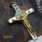 Silver cross pendant with gold Jesus figure on a textured brown background, branded 'Smudge'.