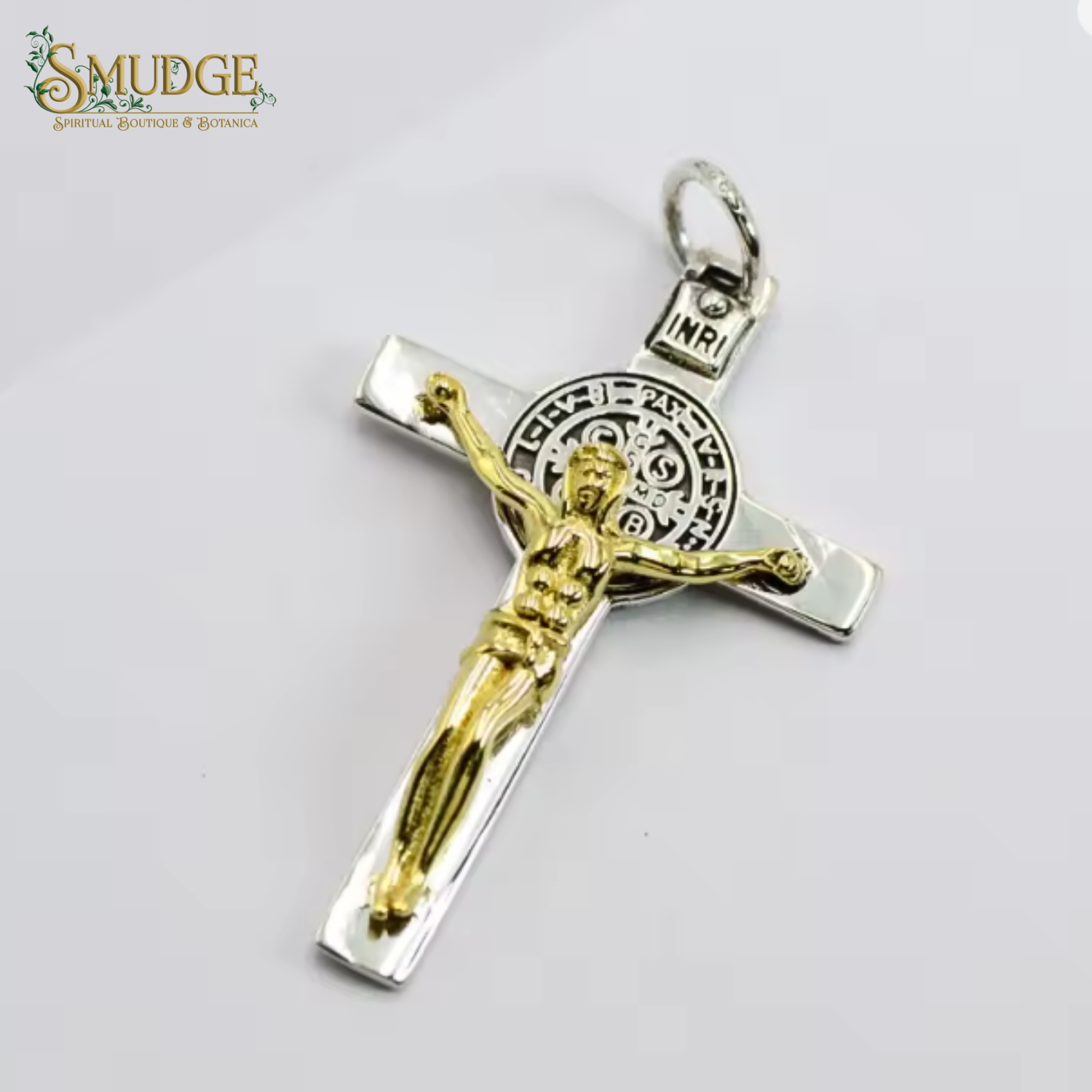 Gold and silver crucifix pendant on a white background with 'Smudge' branding.