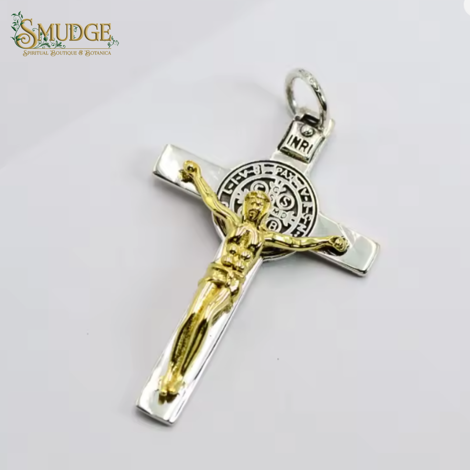 Gold and silver crucifix pendant on a white background with 'Smudge' branding.