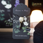 Hand holding Crow Skull Necklace from Venom and Vines on candlelit background with Smudge logo 
