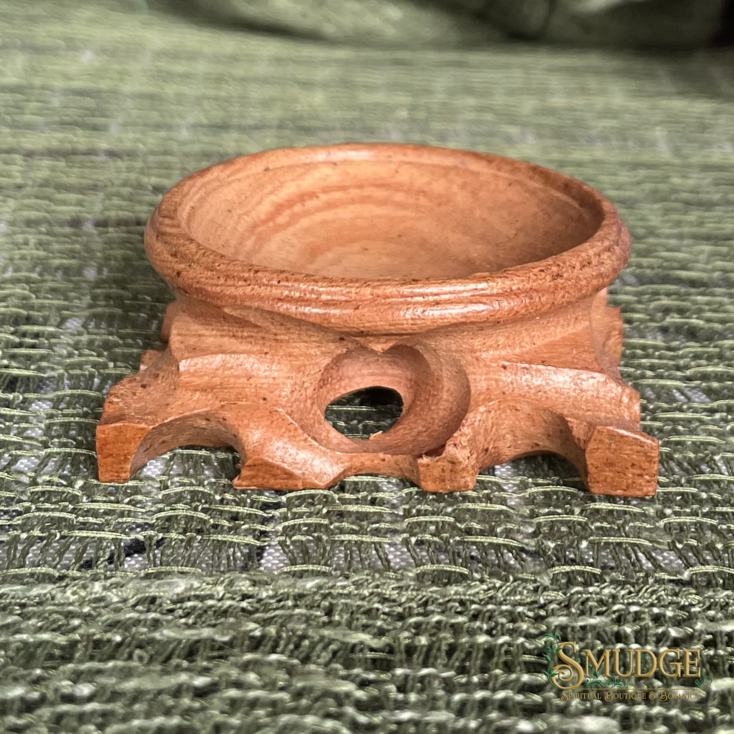 Wooden incense burner on a textured green surface with 'Smudge' branding.
