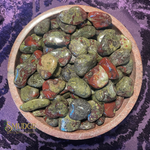 Bowl of polished gemstones on a purple fabric background