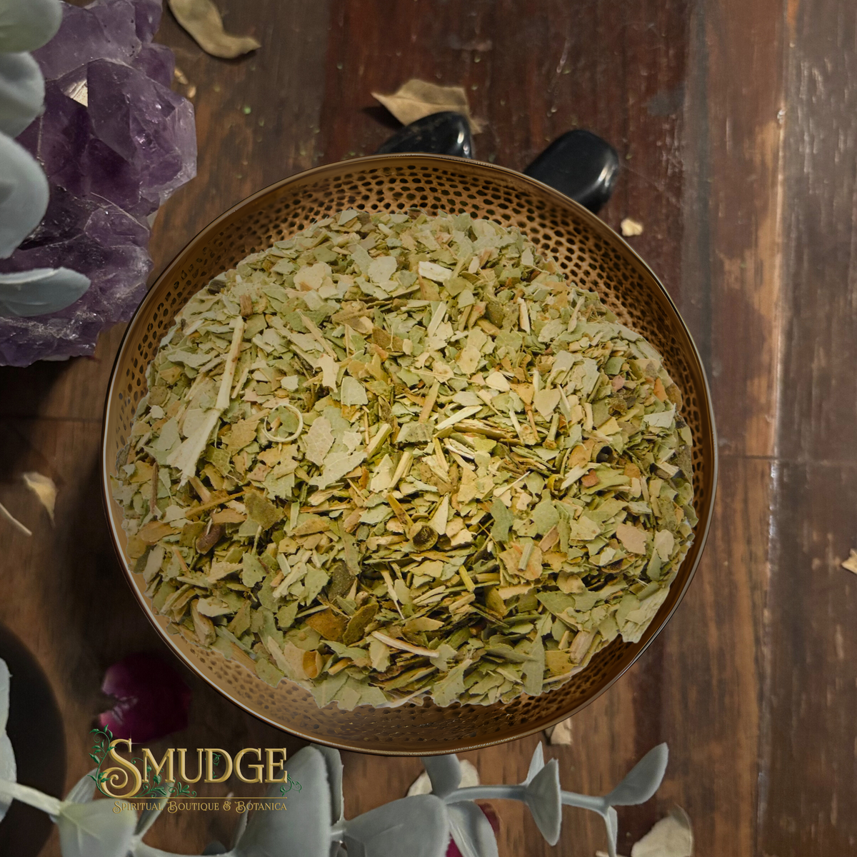 Bowl of dried herbs on a wooden surface with 'The Smudge' branding.