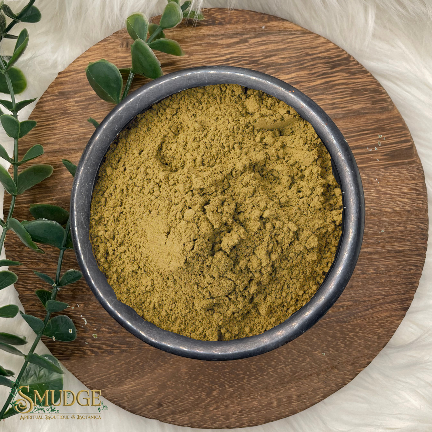 Bowl of green powder on a wooden plate with eucalyptus leaves, branded 'Smudge'.