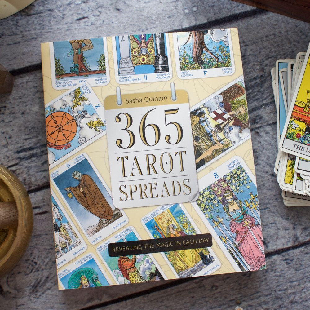 Book titled '365 Tarot Spreads' with tarot cards on a wooden surface.