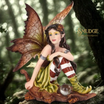Fairy figurine with large wings and striped legs sitting on a rock in a forest setting, brand 'Smudge' visible.