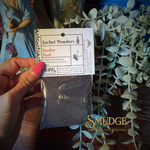 Hand holding a package of 'Goofer Dust' with a label in front of greenery