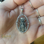 Silver pendant with intricate design held in a hand
