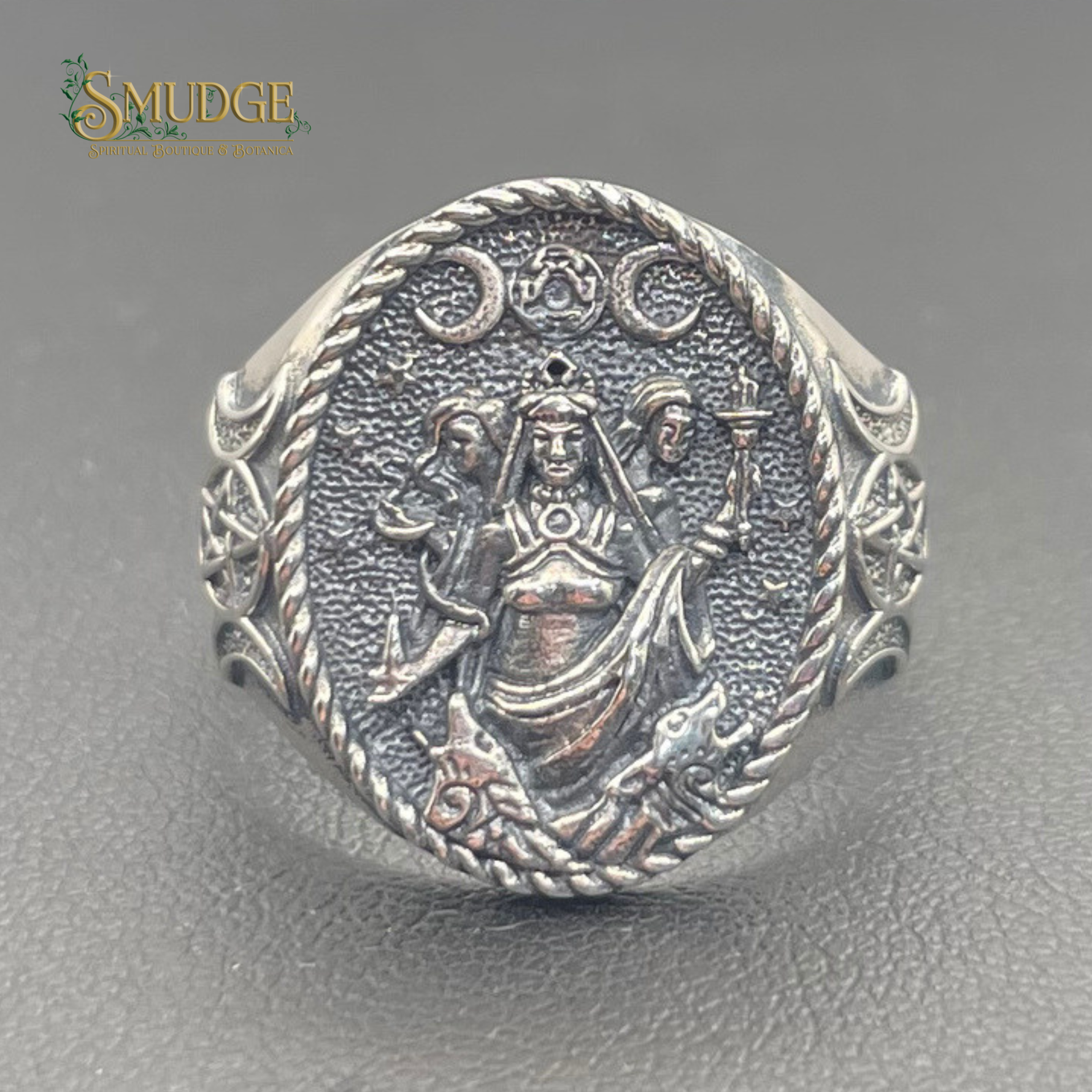 Silver ring with intricate design on a gray background