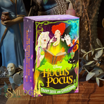 Disney Hocus Pocus Tarot Deck and Guidebook box standing on a wooden surface, surrounded by occult-themed decor including a blue-robed figure, skull, and dried leaves.