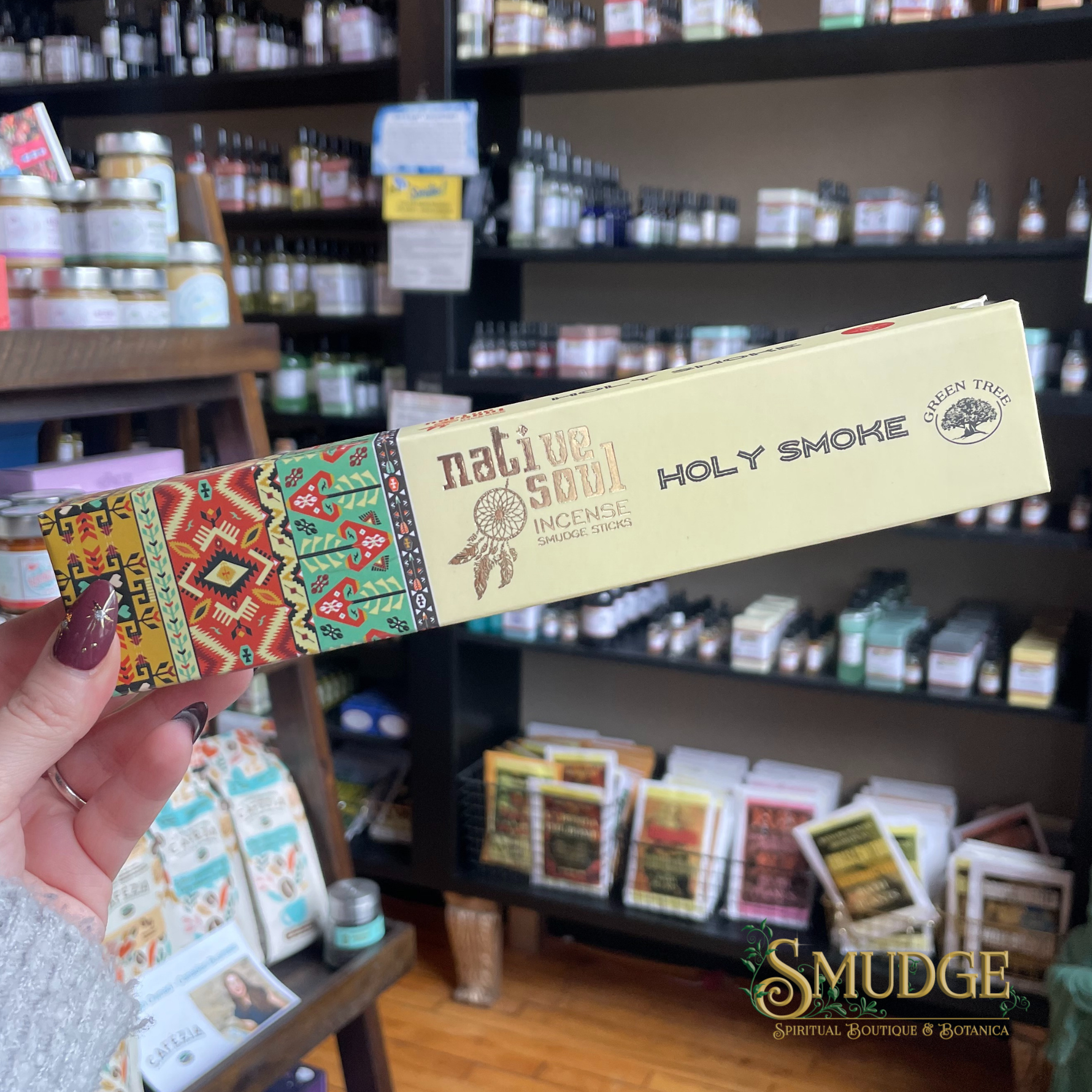 Incense stick packaging held in front of a store shelf with various products.