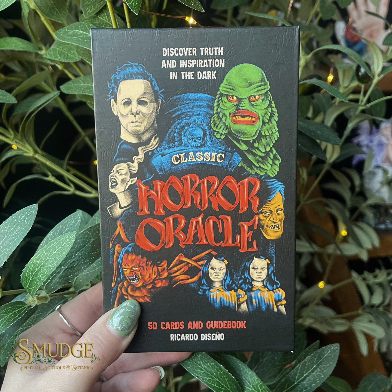 Classic Horror Oracle deck held in front of a green plant background