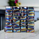 Stack of rainbow-colored metallic blocks on a marble surface with a blurred background