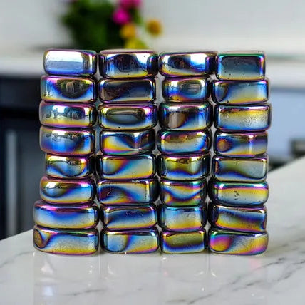 Stack of rainbow-colored metallic blocks on a marble surface with a blurred background