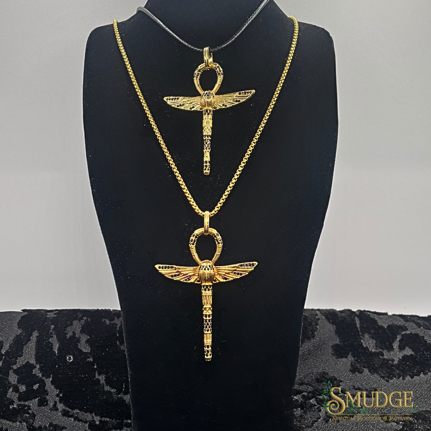 Gold necklace with an ankh pendant on a black bust against a gray background