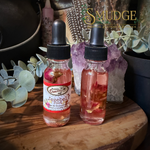 A bottle of Jezebel root conjure spell oil with roses on a wood table.