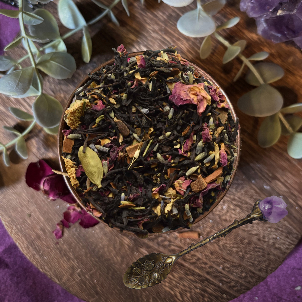 Tea leaves in a wooden bowl with eucalyptus leaves and amethyst crystals on a purple fabric background