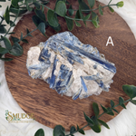 Crystal rock on a wooden board with greenery, featuring the brand 'Smudge'.