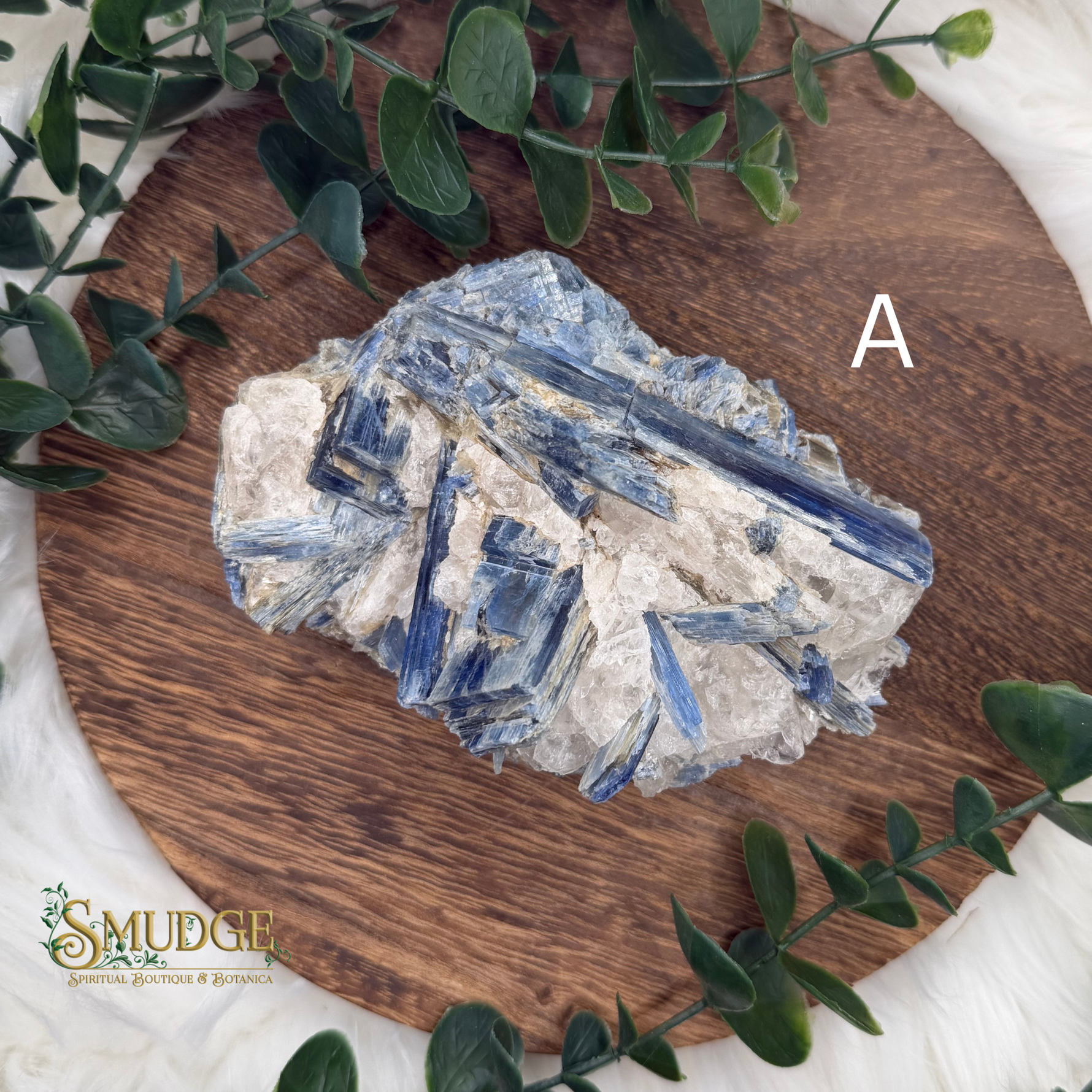 Crystal rock on a wooden board with greenery, featuring the brand 'Smudge'.