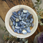 blue tumbled kyanite stones in a bowl on a wooden table.