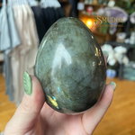 Person holding a large labradorite stone with a blurred background