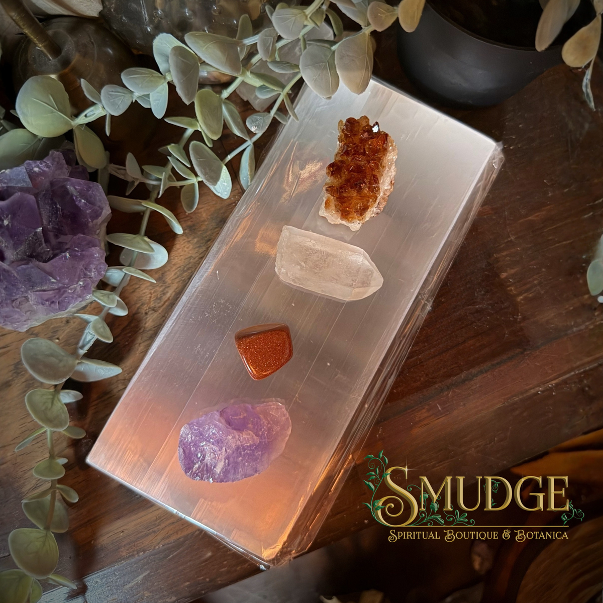 A large selenite slab on a wooden table with various crystals on it.