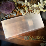 A large selenite square plate on a wooden table.